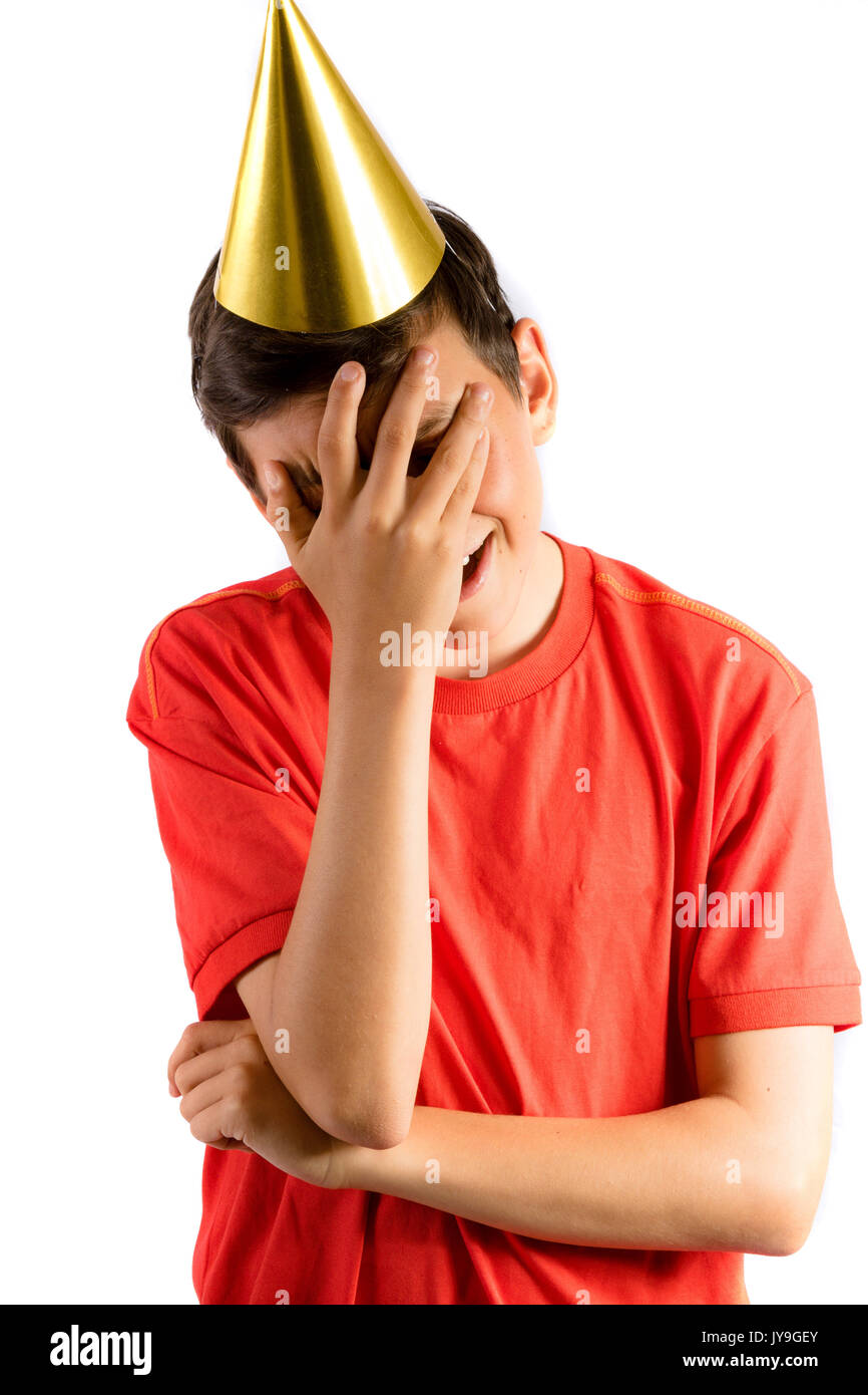 Young teenage boy isolated on white covering his eyes at a party Stock Photo