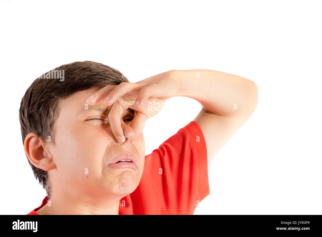 Young teenage boy isolated on a white background holding his nose Stock