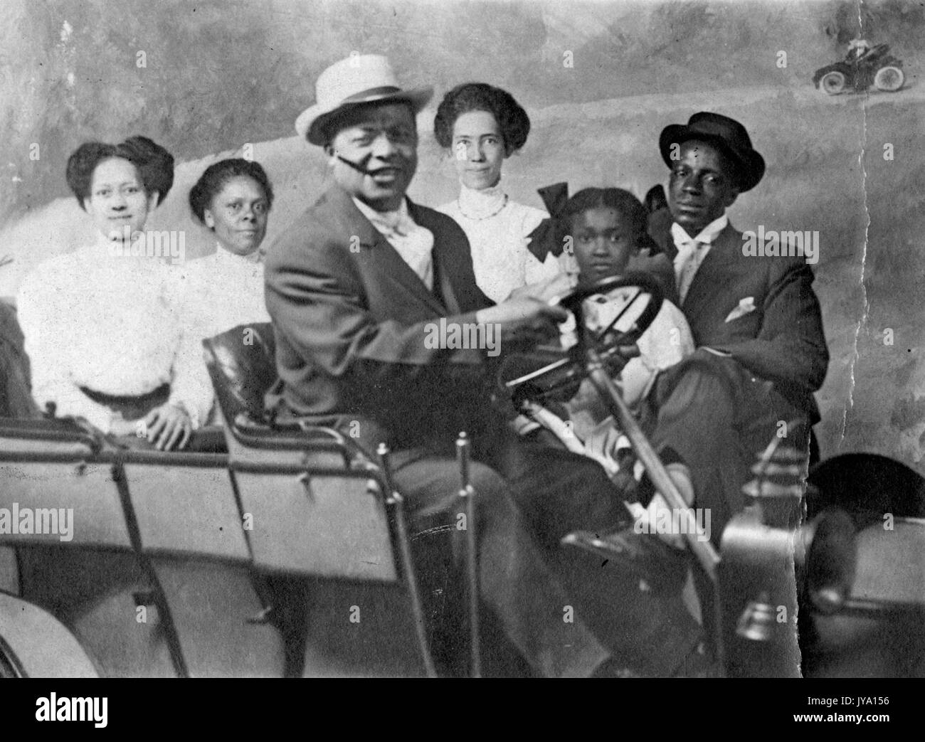 Portrait of African-American family, with automobile, in photographic studio, 1930. Stock Photo