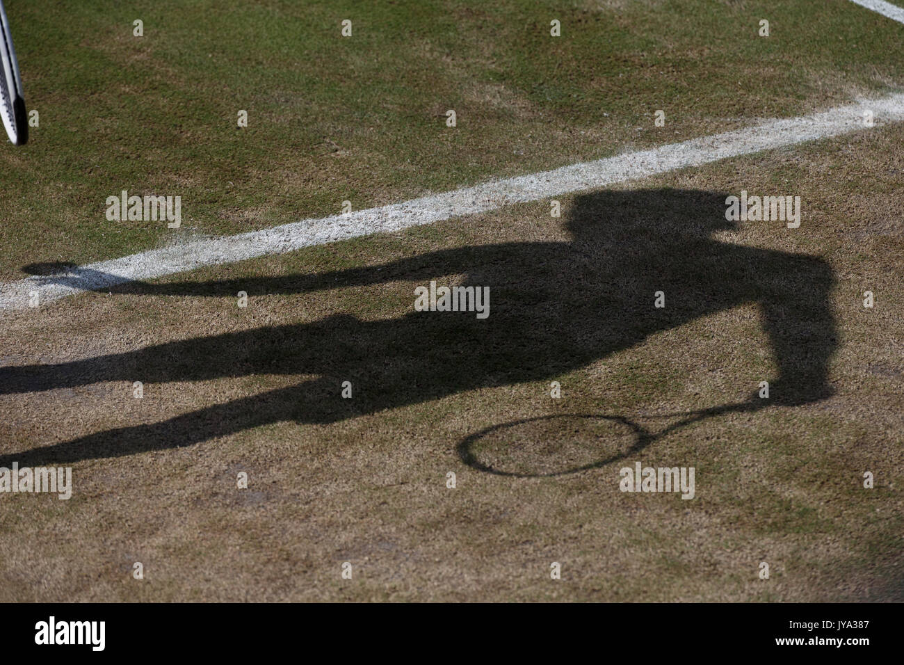 Shadow of tennis player on worn dry lawn at Wimbledon Championships 2017, London, Great Britain, United Kingdom. Stock Photo