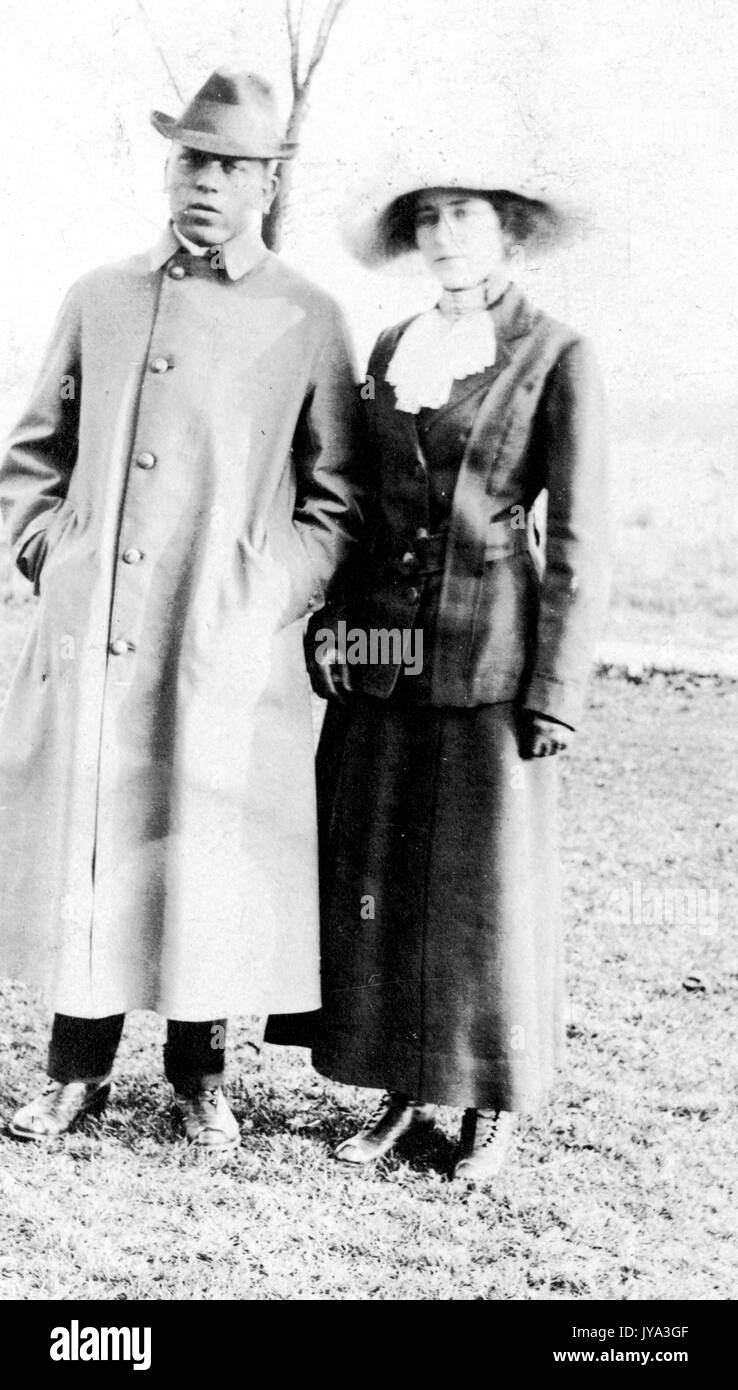 African American man and woman standing on the lawn and posing for a photograph, wearing cold weather clothing, the man with his hands in pocket, woman of a light skin complexion wearing a wide brimmed hat and standing next to him, 1932. Stock Photo