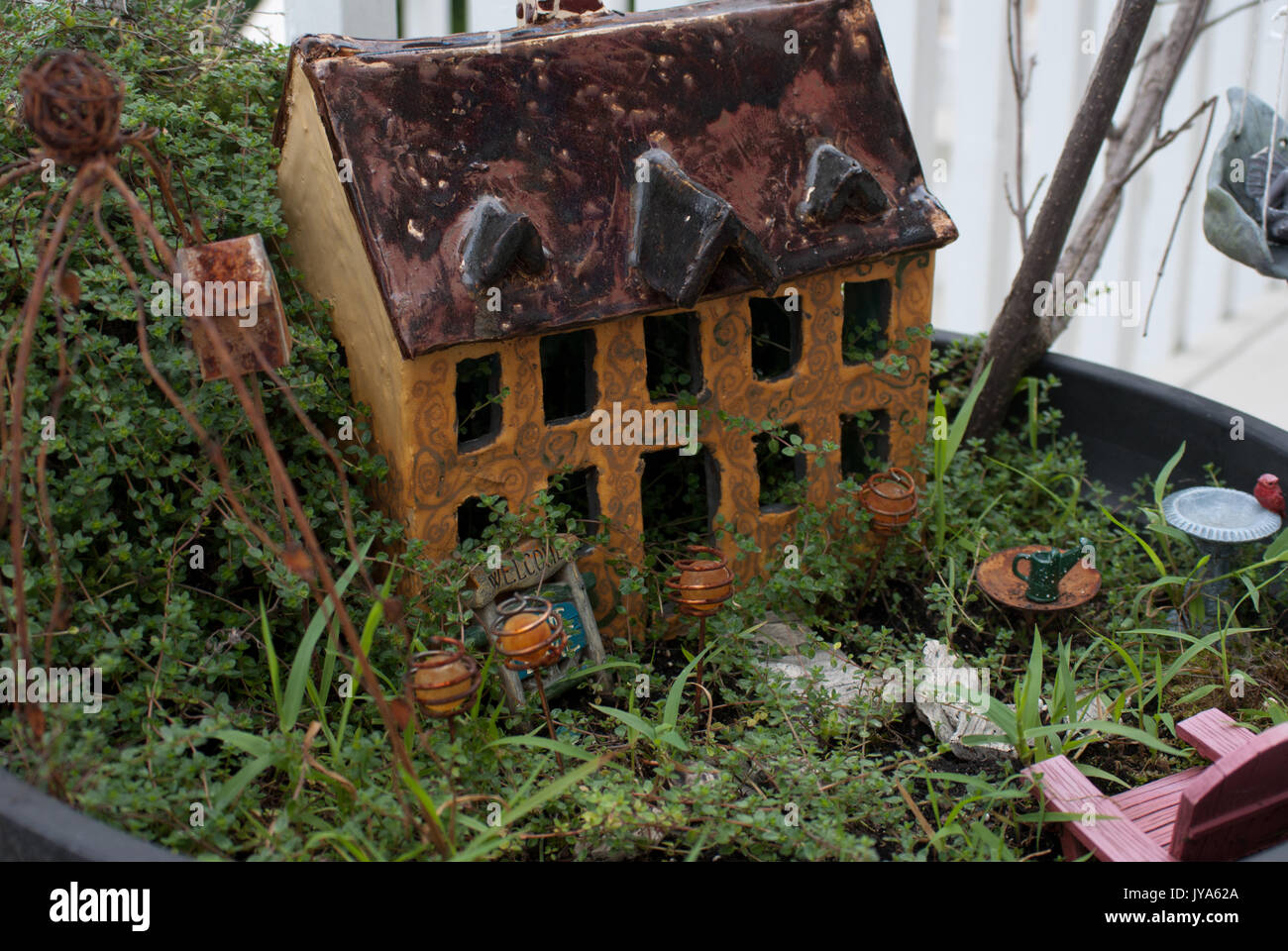 Yellow ceramic fairy house  in a leafy garden Stock Photo 