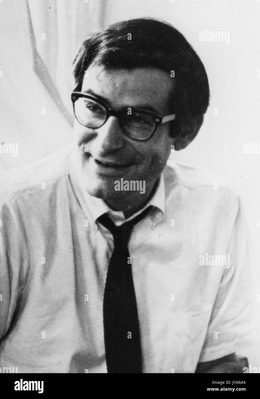 Speaker for the Milton S. Eisenhower Symposium, a lecture series at Johns Hopkins University, David Halberstam, American journalist and historian, smiles off camera wearing a worn-in white button-down with a loose black tie and glasses. 1975. Stock Photo