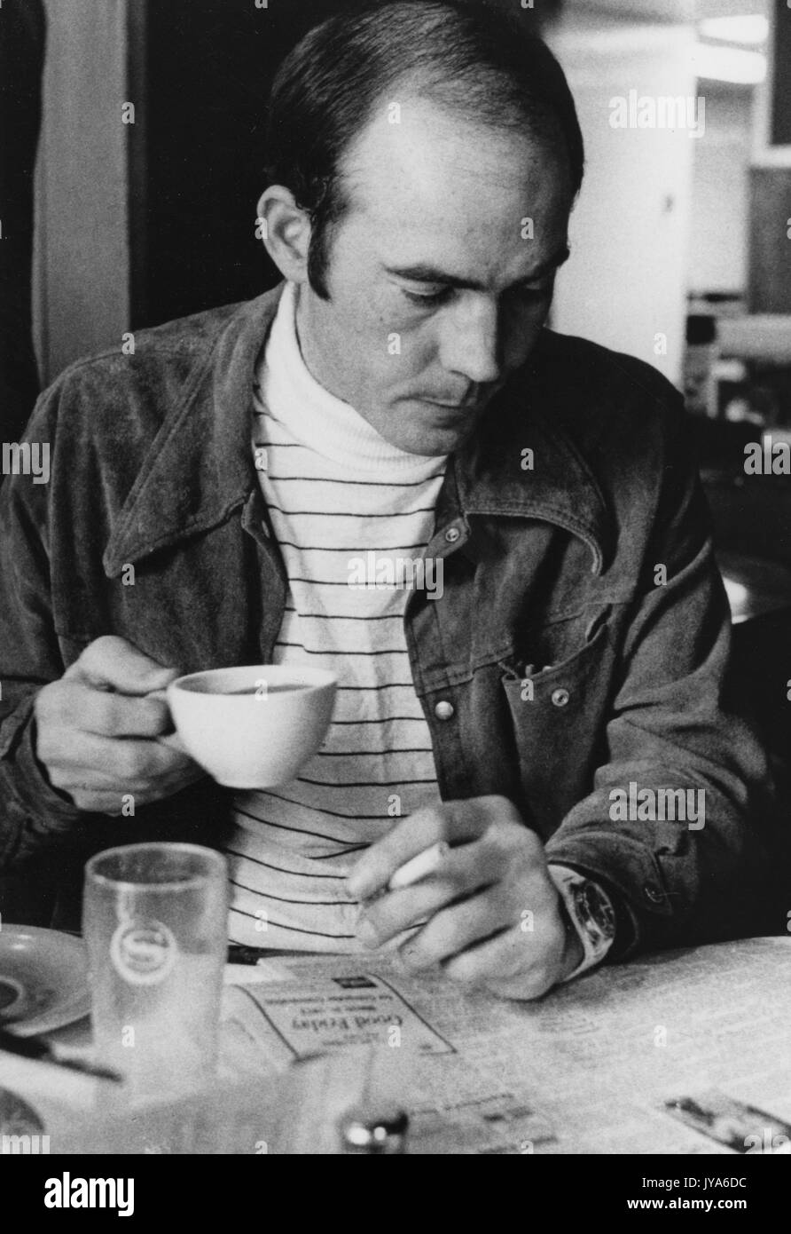 A half-length portrait of founder of the gonzo journalism movement Hunter Thompson as he intently reads the newspaper while drinking a cup of coffee, who spoke at the Milton S. Eisenhower Symposium, a lecture series at Johns Hopkins University, Baltimore, Maryland. 1975. Stock Photo