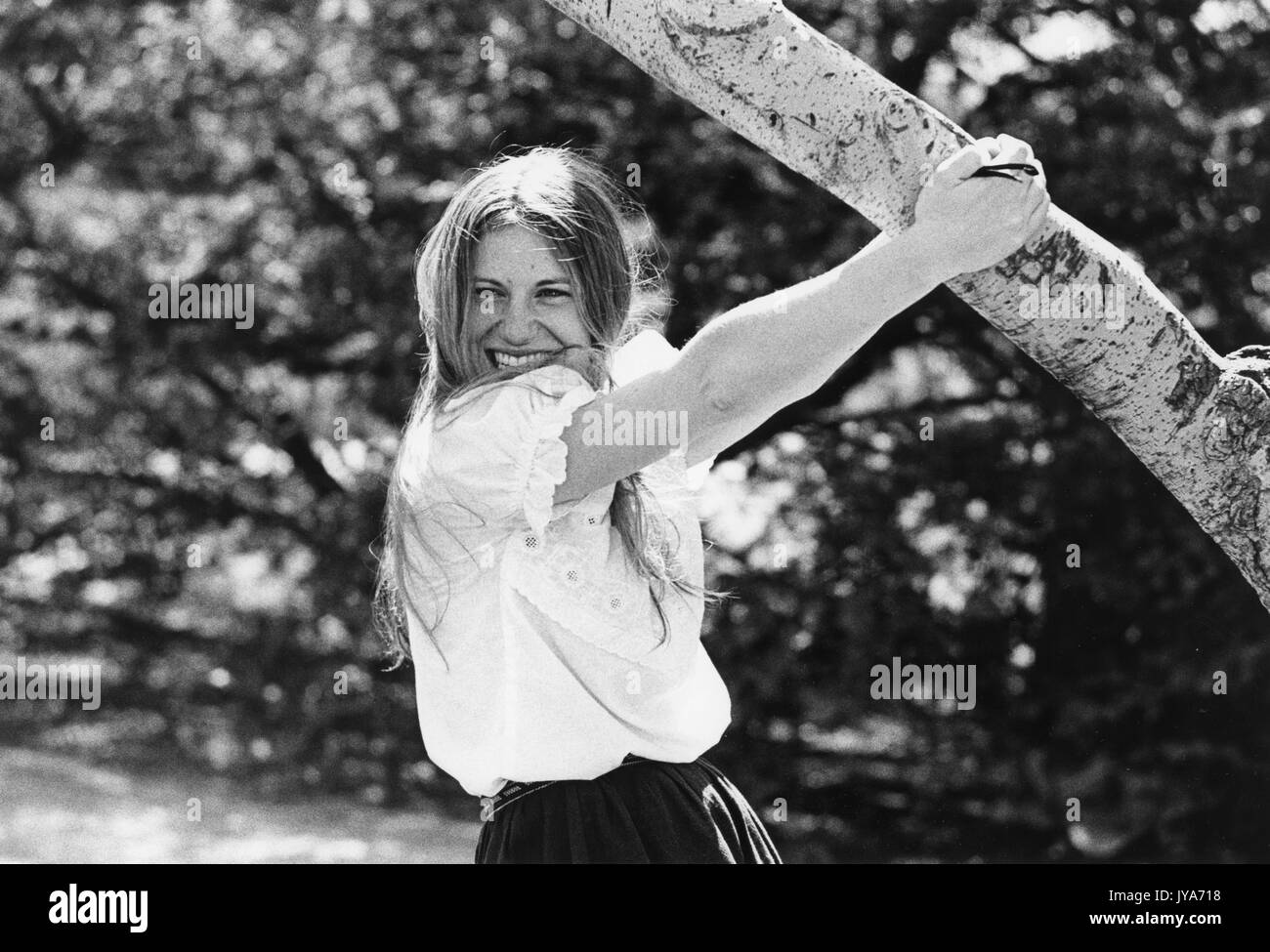 A photograph of a female undergraduate student at Johns Hopkins University hanging off of a tree on campus during the first years of the undergraduate program's admittance of women, in Baltimore, Maryland. 1970. Stock Photo