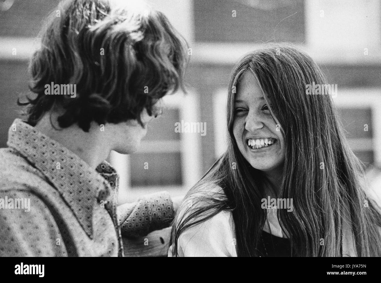 A photograph of a smiling undergraduate woman socializing with an undergraduate male as they sit on a bench on the Homewood campus of the Johns Hopkins University in Baltimore, Maryland during the first years that the university's undergraduate program admitted women. 1970. Stock Photo