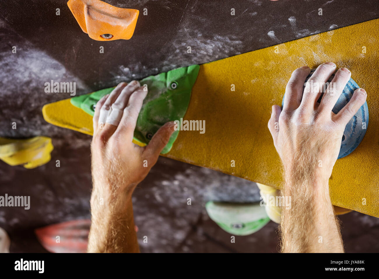 Closeup of rock climber's hands gripping handholds in indoor climbing