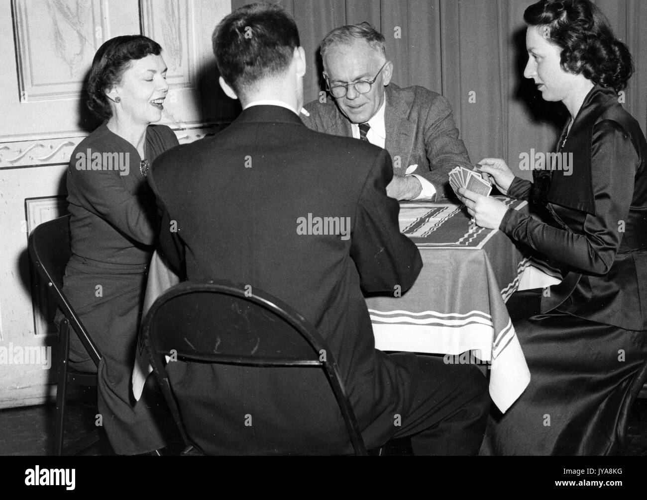 Four individuals sitting around a table playing cards for 'The Truth About Biological Warfare' segment on the Johns Hopkins Science Review television show, May, 1951. Stock Photo