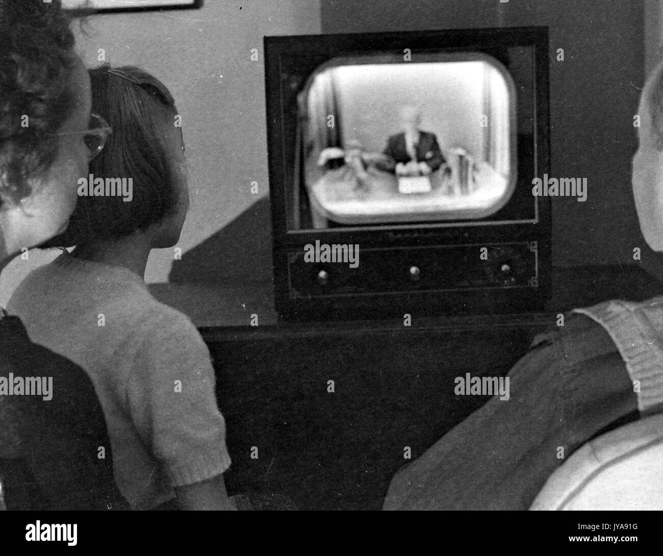 Family gathered around television set to watch American television host Lynn Poole on the Johns Hopkins Science Review, 1951. Stock Photo