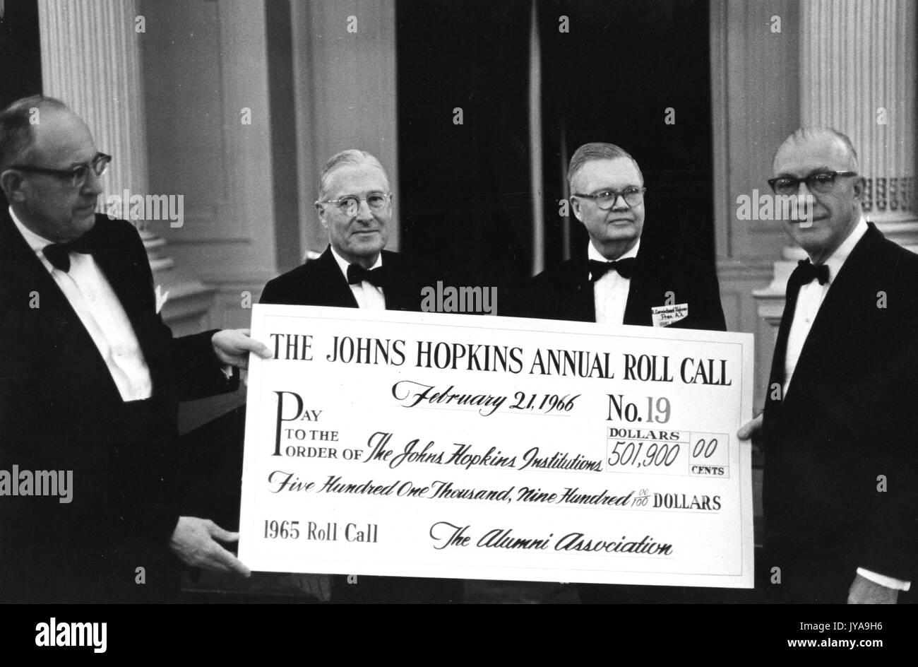Milton Stover Eisenhower (right), president of Johns Hopkins University, standing with colleagues to present a check amounting to the funds raised by the Alumni Association for that year, February 21, 1966. Stock Photo
