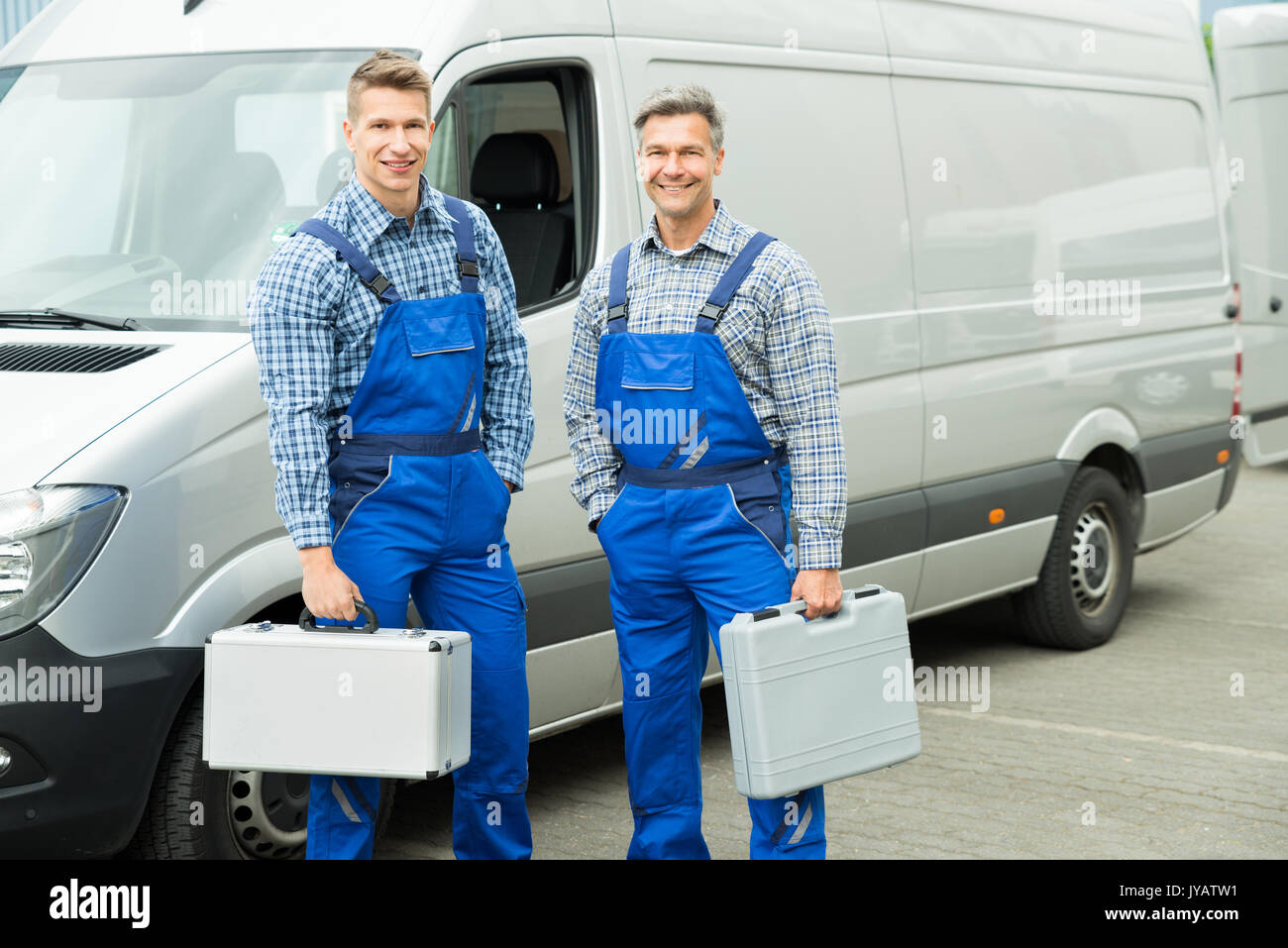 Young Happy Male Worker With Toolbox Standing In Front Of Van Stock Photo