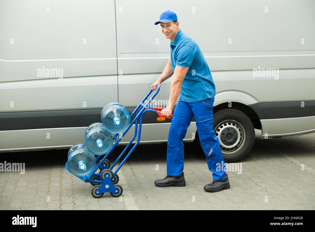 Young Happy Delivery Man Holding Trolley With Water Bottles Stock Photo -  Alamy