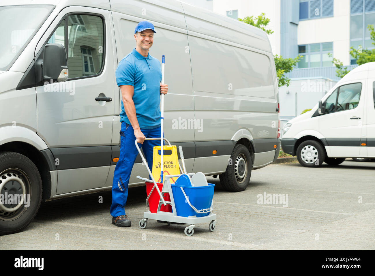 Happy Male Cleaner In Front Of Van With Cleaning Equipments Stock Photo