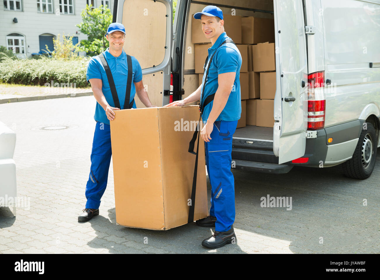 Two Happy Movers In Blue Uniform Loading Boxes In Truck Stock Photo