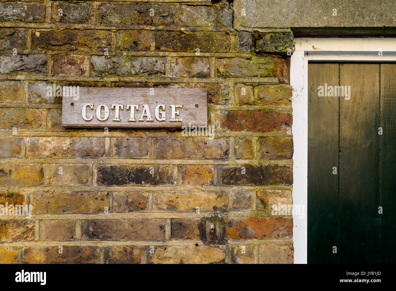 Cottage wooden sign on a brick wall. Landscape format. Stock Photo
