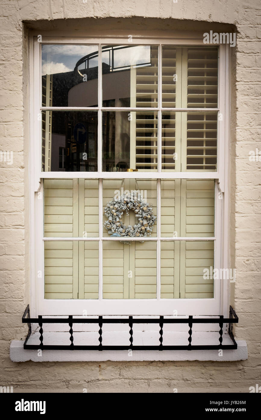 Sash window decorated with a silver Christmas garland in London (UK). Portrait format. Stock Photo