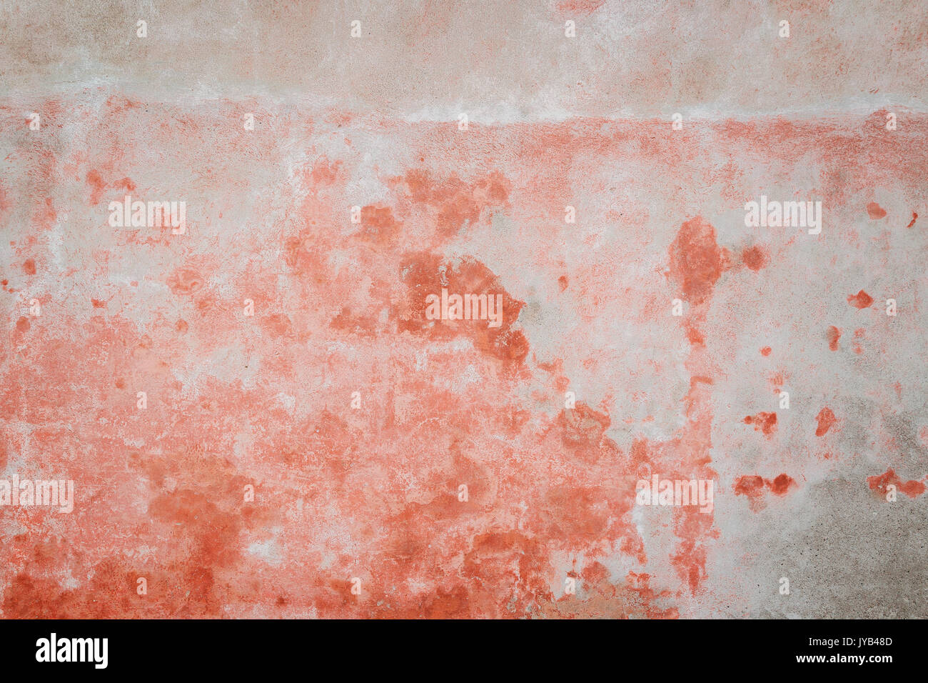 Weathered and aged concrete wall, bleached red paint peeled off. Texture background with
