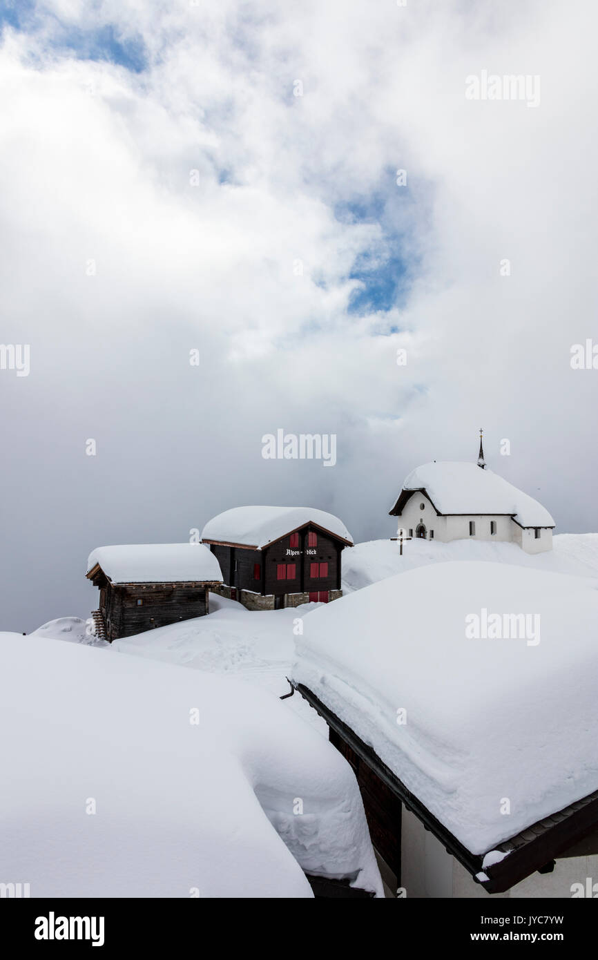 Snow covered mountain huts and church surrounded by low clouds Bettmeralp district of Raron canton of Valais Switzerland Europe Stock Photo