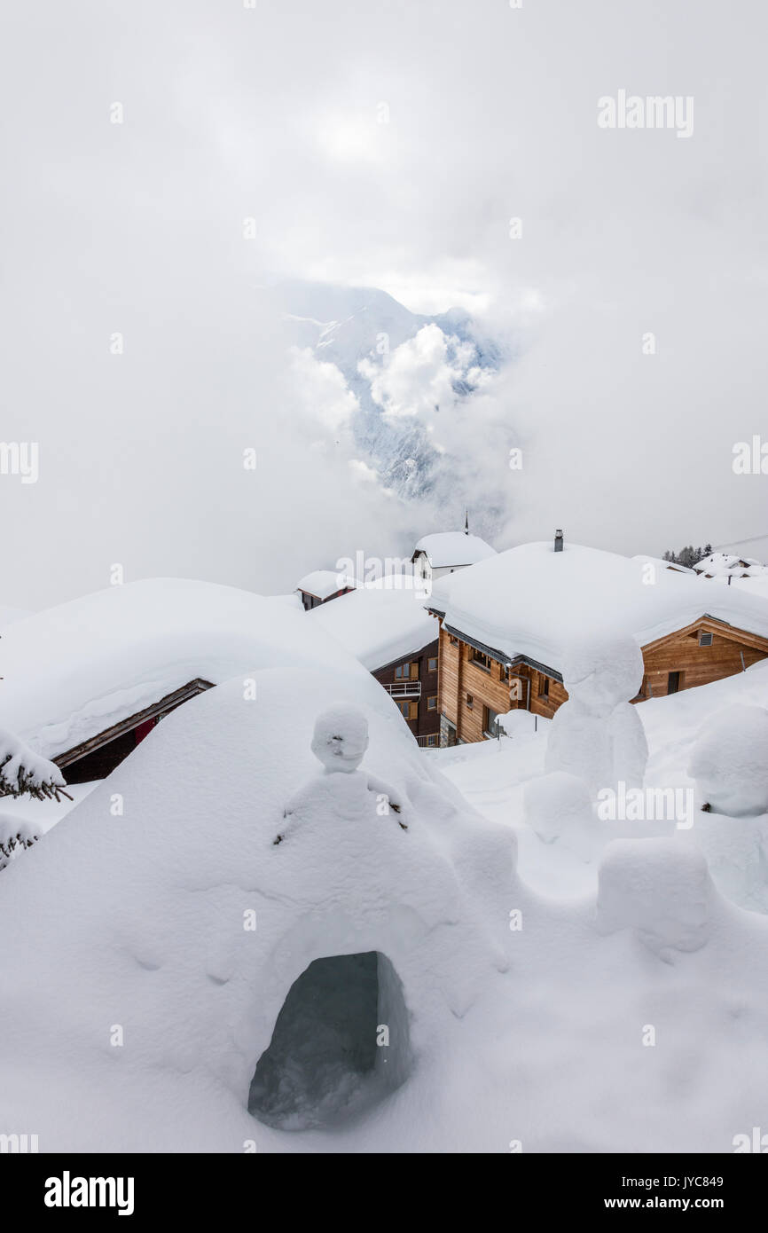 Clouds on the snowman and the mountain huts covered with snow Bettmeralp district of Raron canton of Valais Switzerland Europe Stock Photo