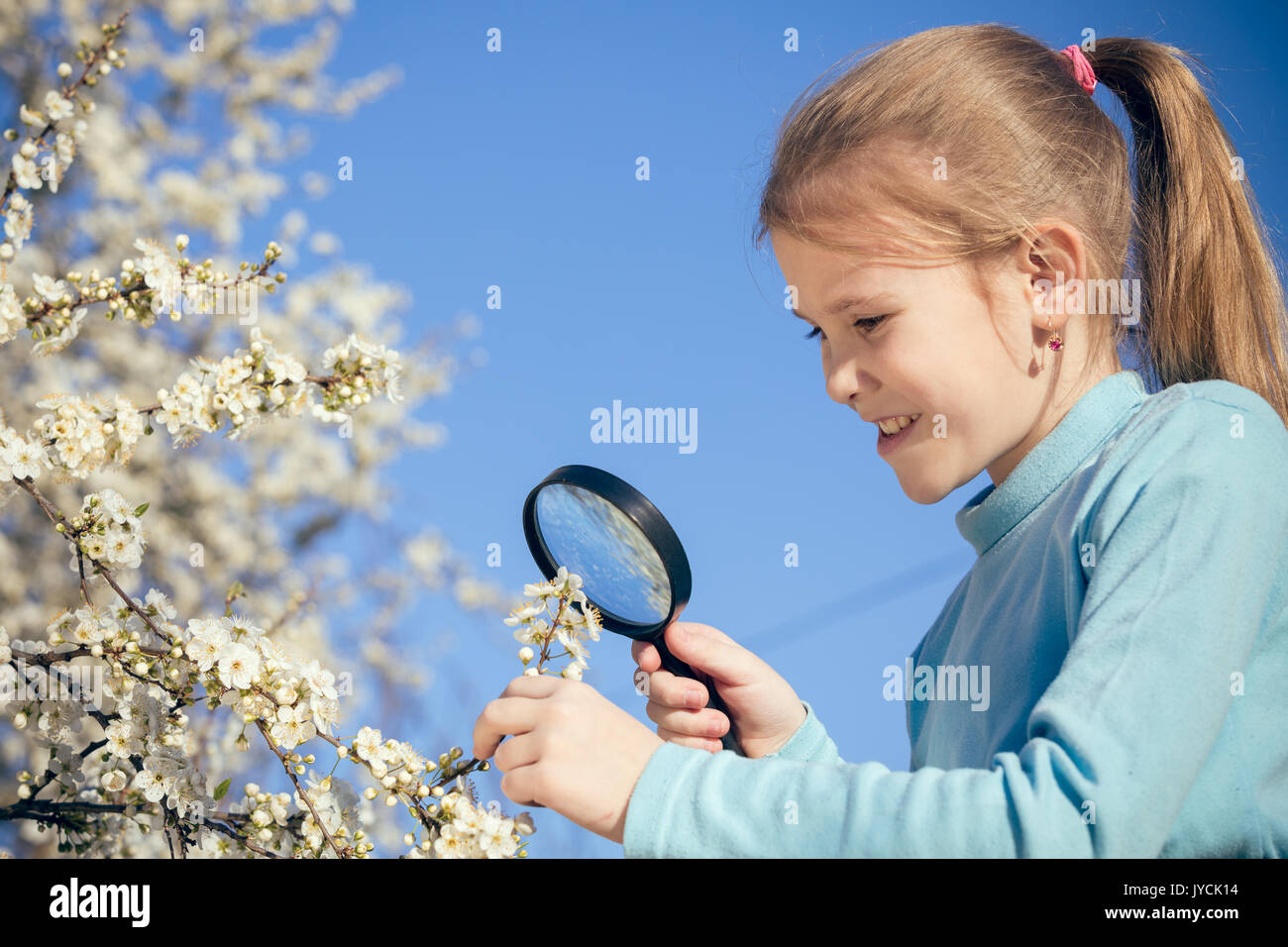 Happy little girl exploring nature with magnifying glass at the day ...