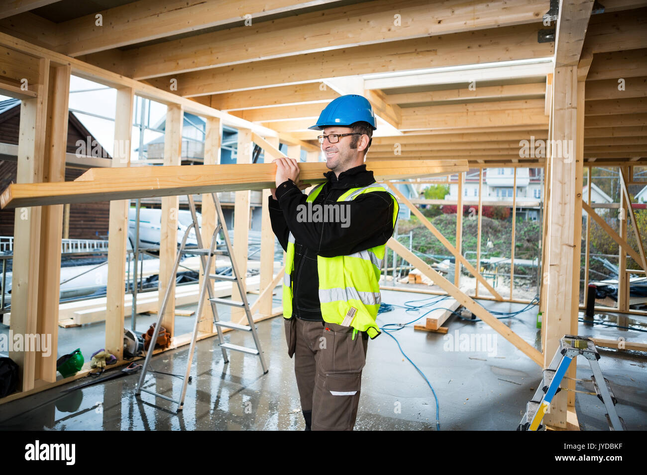 Mature Carpenter Carrying Wood At Construction Site Stock Photo