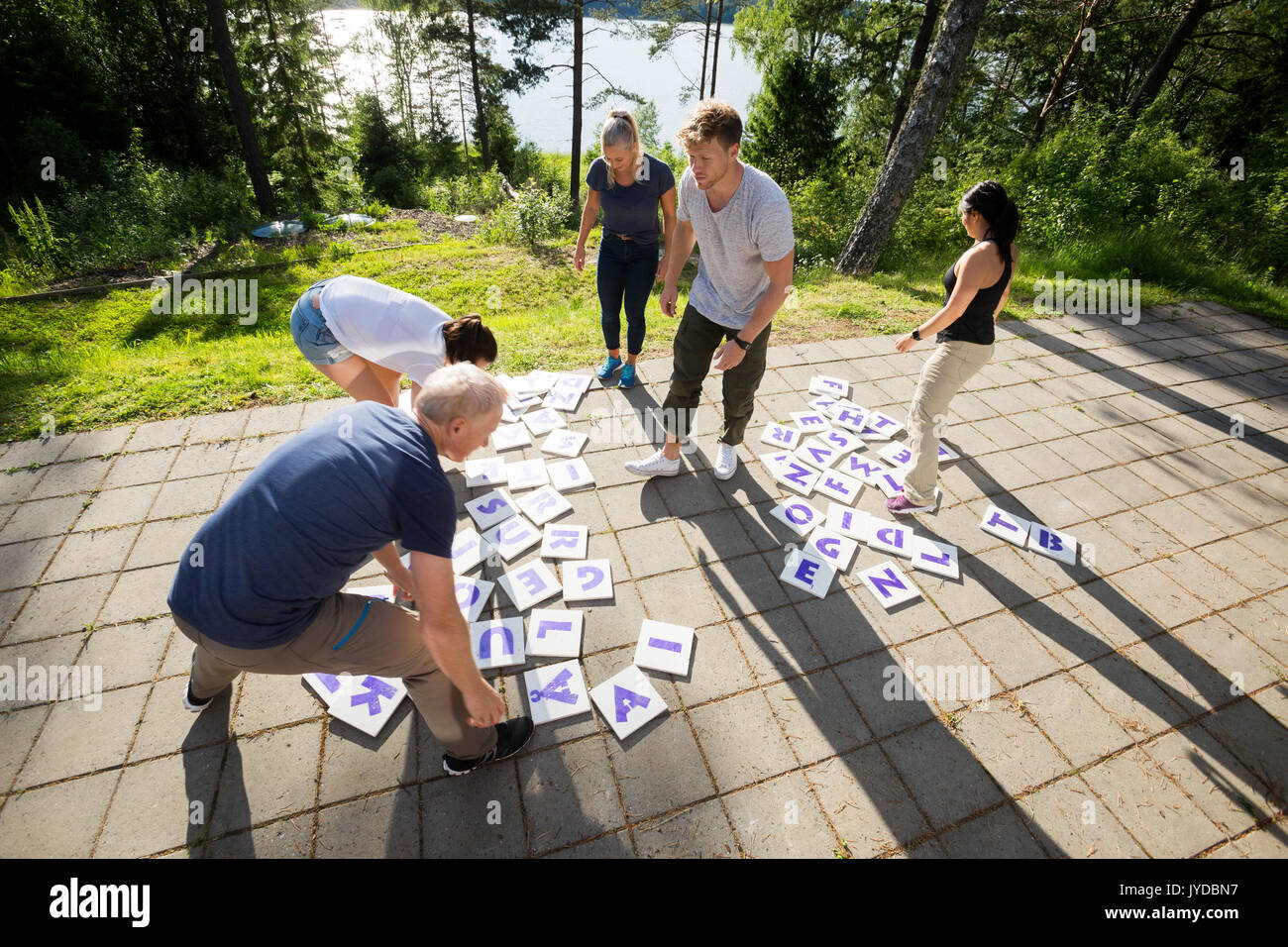 High Angle View Of Friends Solving Crossword Puzzle On Patio Stock