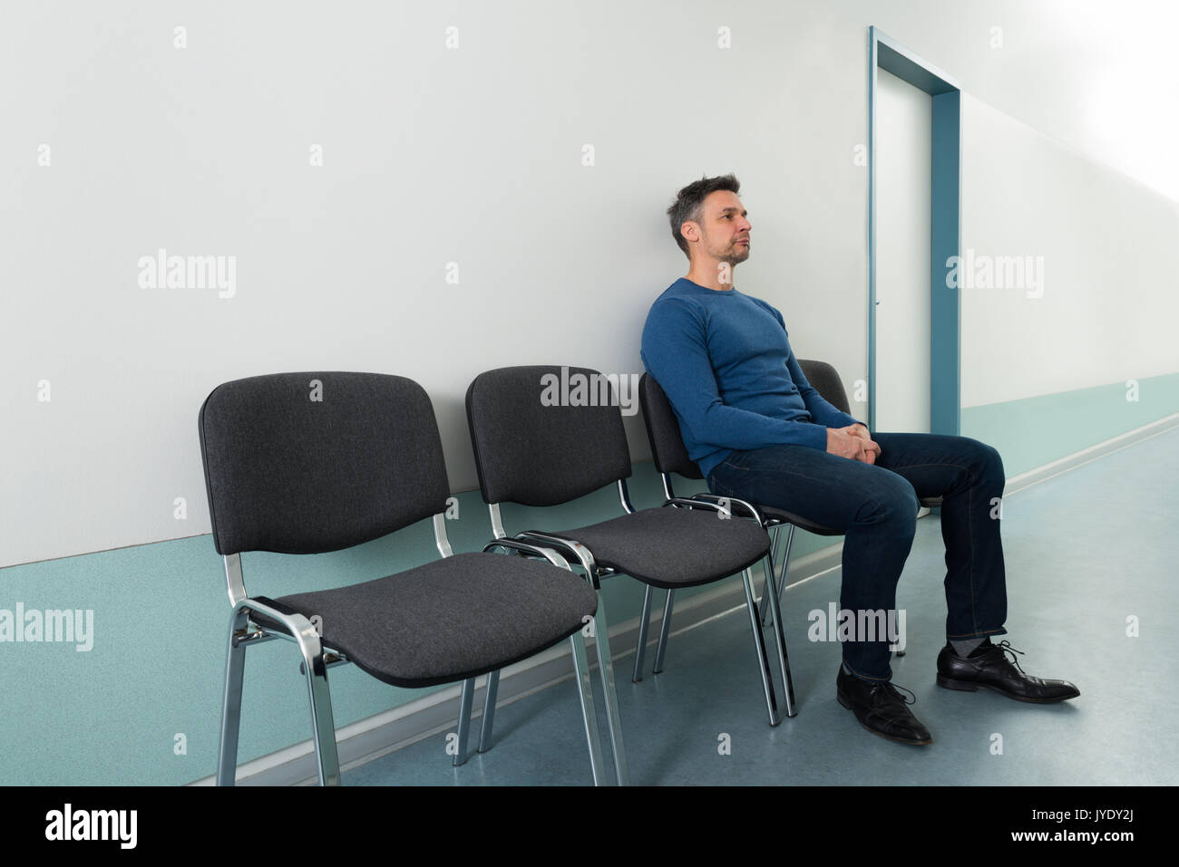 Portrait Of A Mid-adult Man Sitting On Chair In Hospital Stock Photo