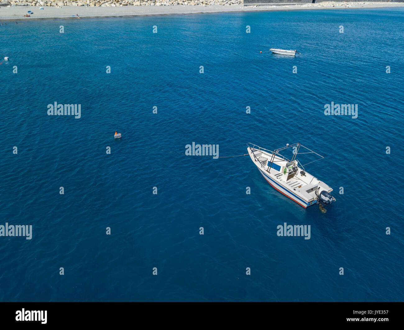 Aerial view of a moored boat floating on a transparent sea. Diving relaxation and summer vacations. Italian coasts, beaches and rocks Stock Photo