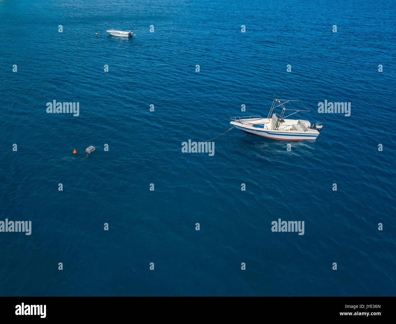Aerial view of a moored boat floating on a transparent sea. Diving relaxation and summer vacations. Italian coasts, beaches and rocks Stock Photo