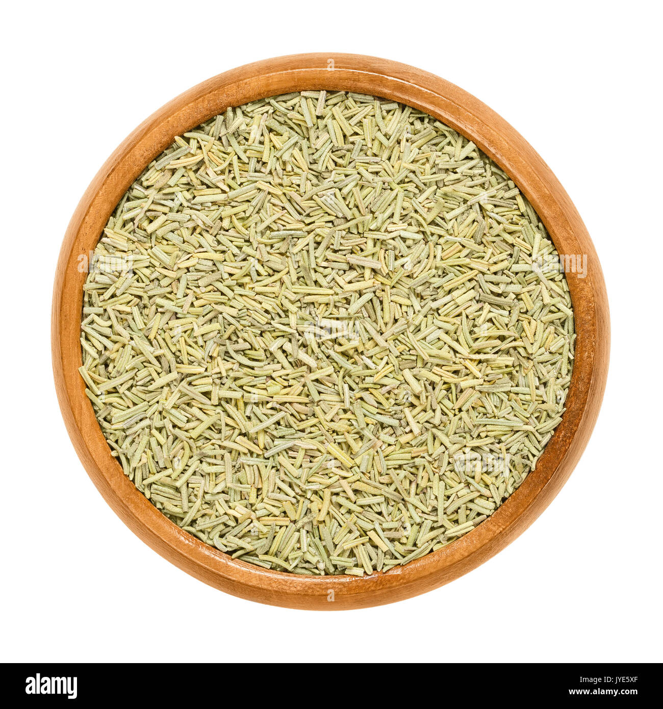 Rosemary dried in wooden bowl. Sliced needle like leaves of Rosmarinus officinalis. Herb with aromatic olive green leaves and a bitter taste. Stock Photo