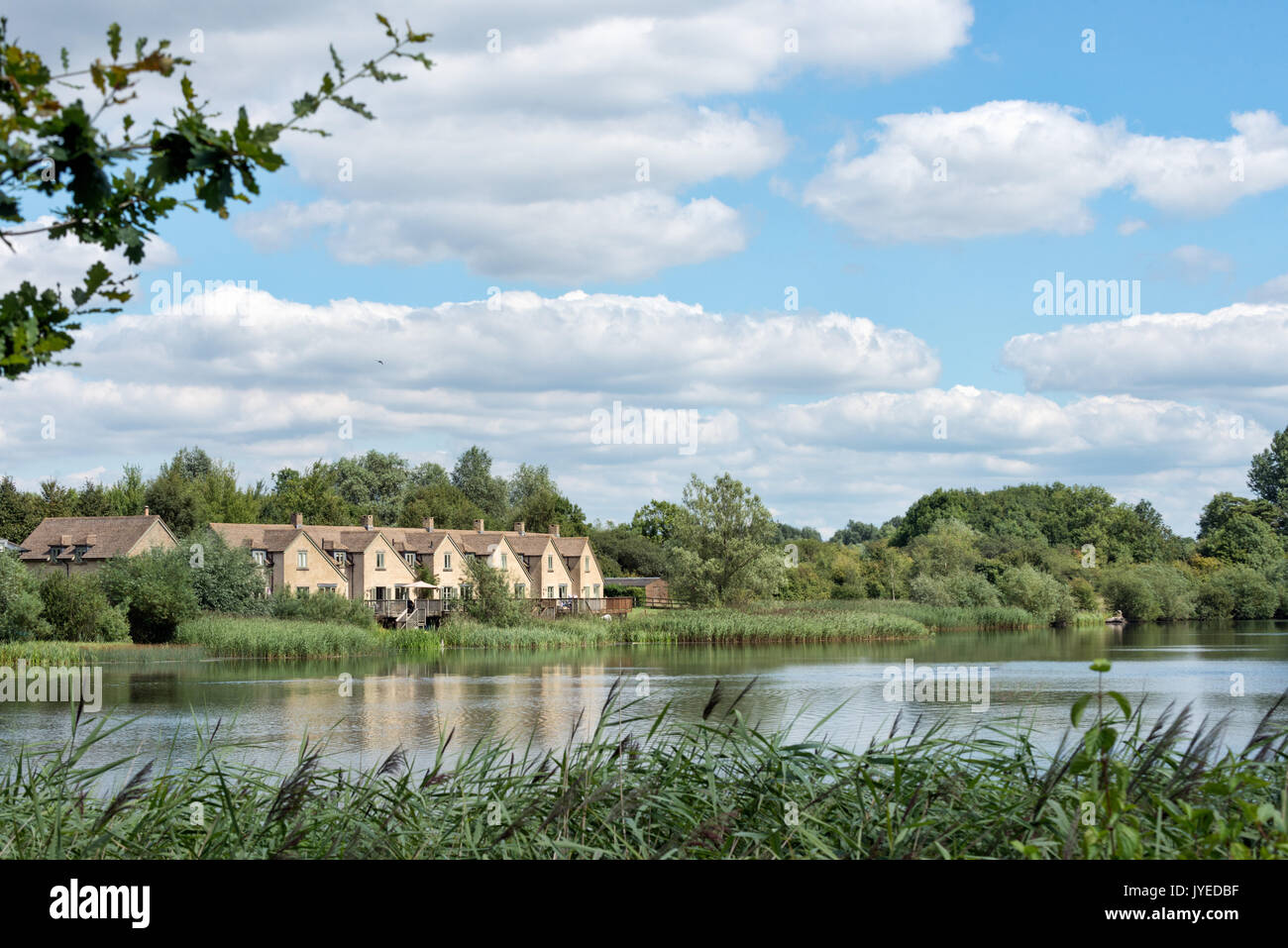A view across Somerford Lagoon  towards Mill Village on the Lower on the Lower Mill Estate near Somerford Keynes in the Cotswolds, UK Stock Photo