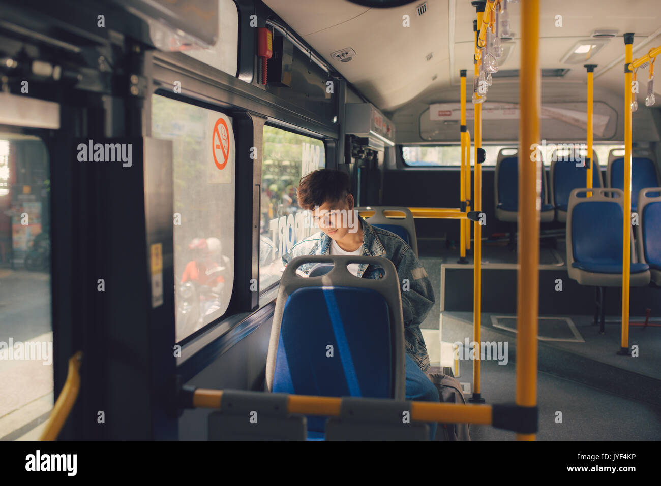 Young man sitting in city bus and reading a book. Stock Photo