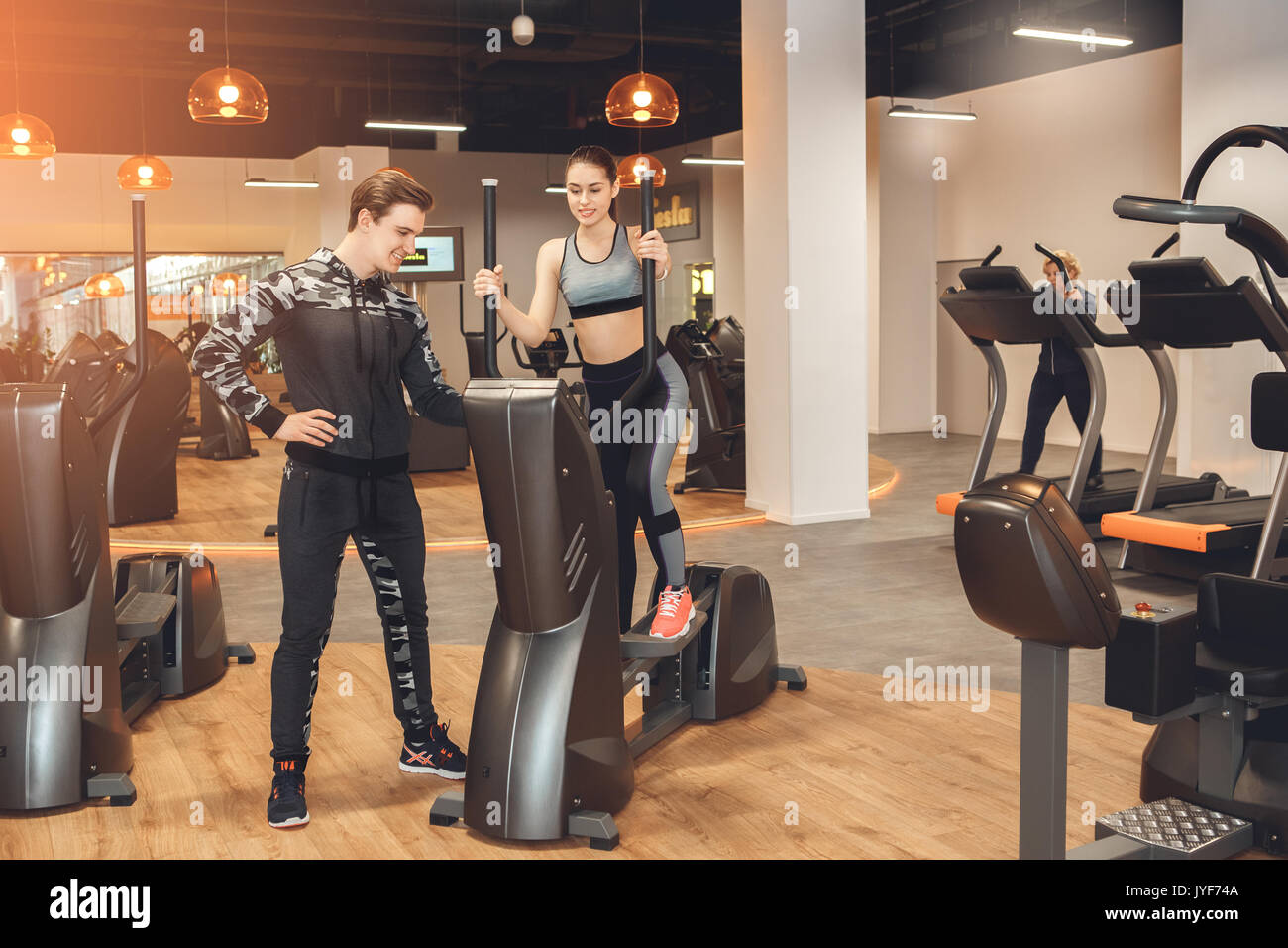 Young man and woman training in gym body workout elliptical trainer ...