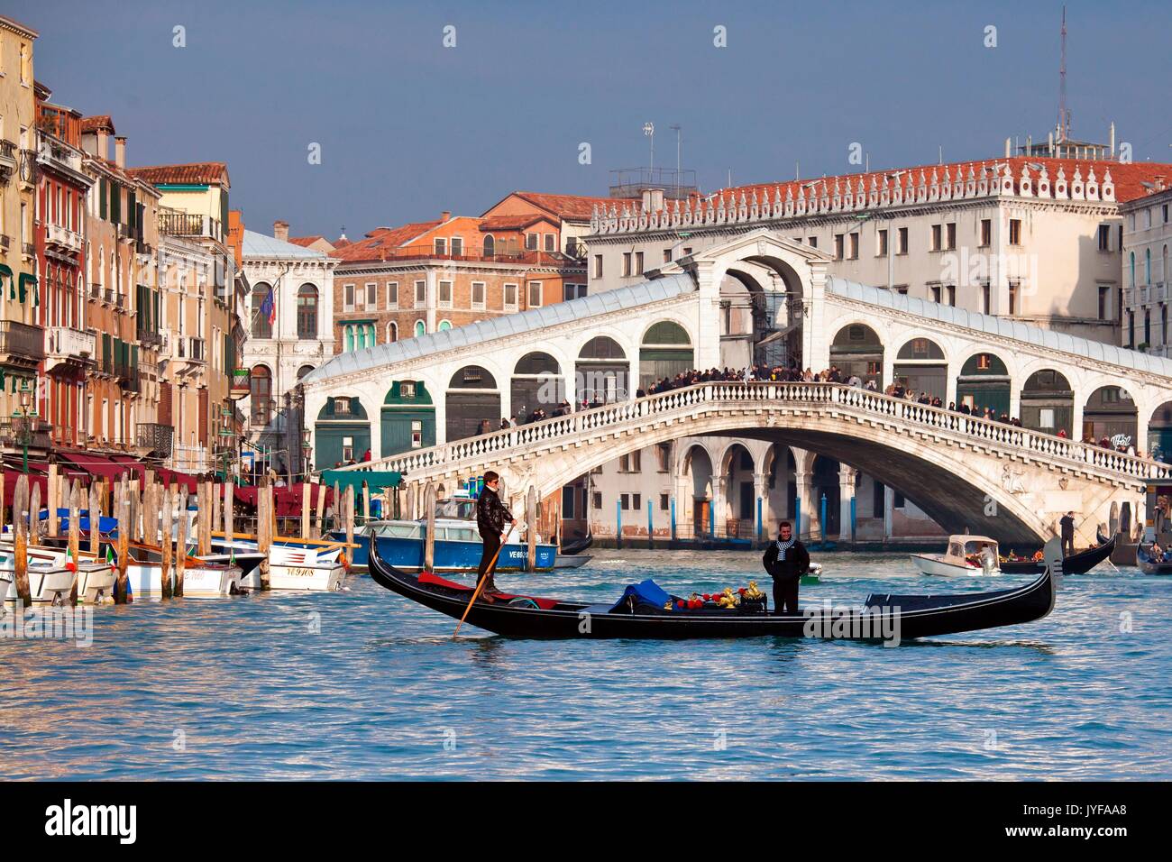 A gondola crossing the Grand Canal right in front of the Rialto Bridge, one of the most recognizable Venetian landmarks  Venice, Veneto Italy Europe Stock Photo