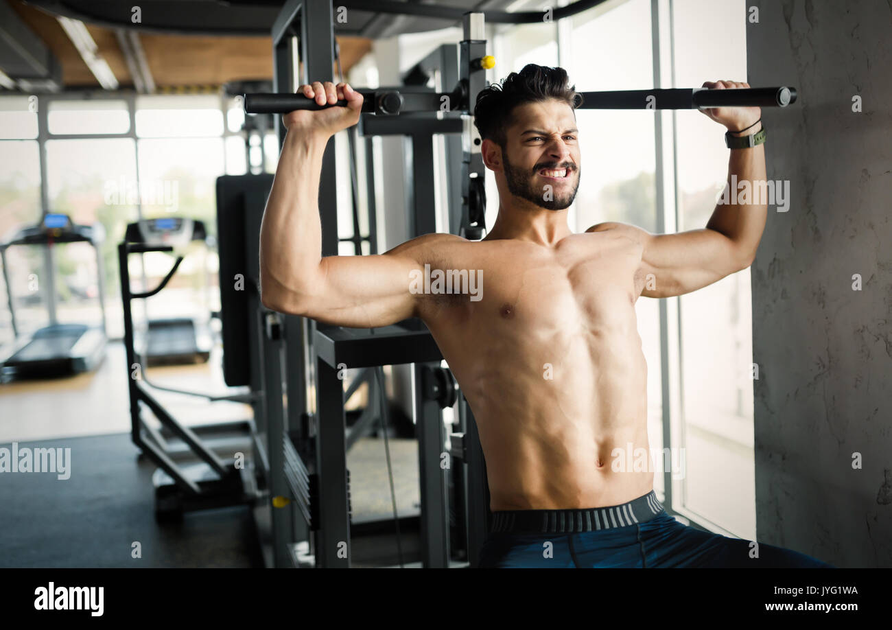 Young bodybuilder training in gym on machine Stock Photo