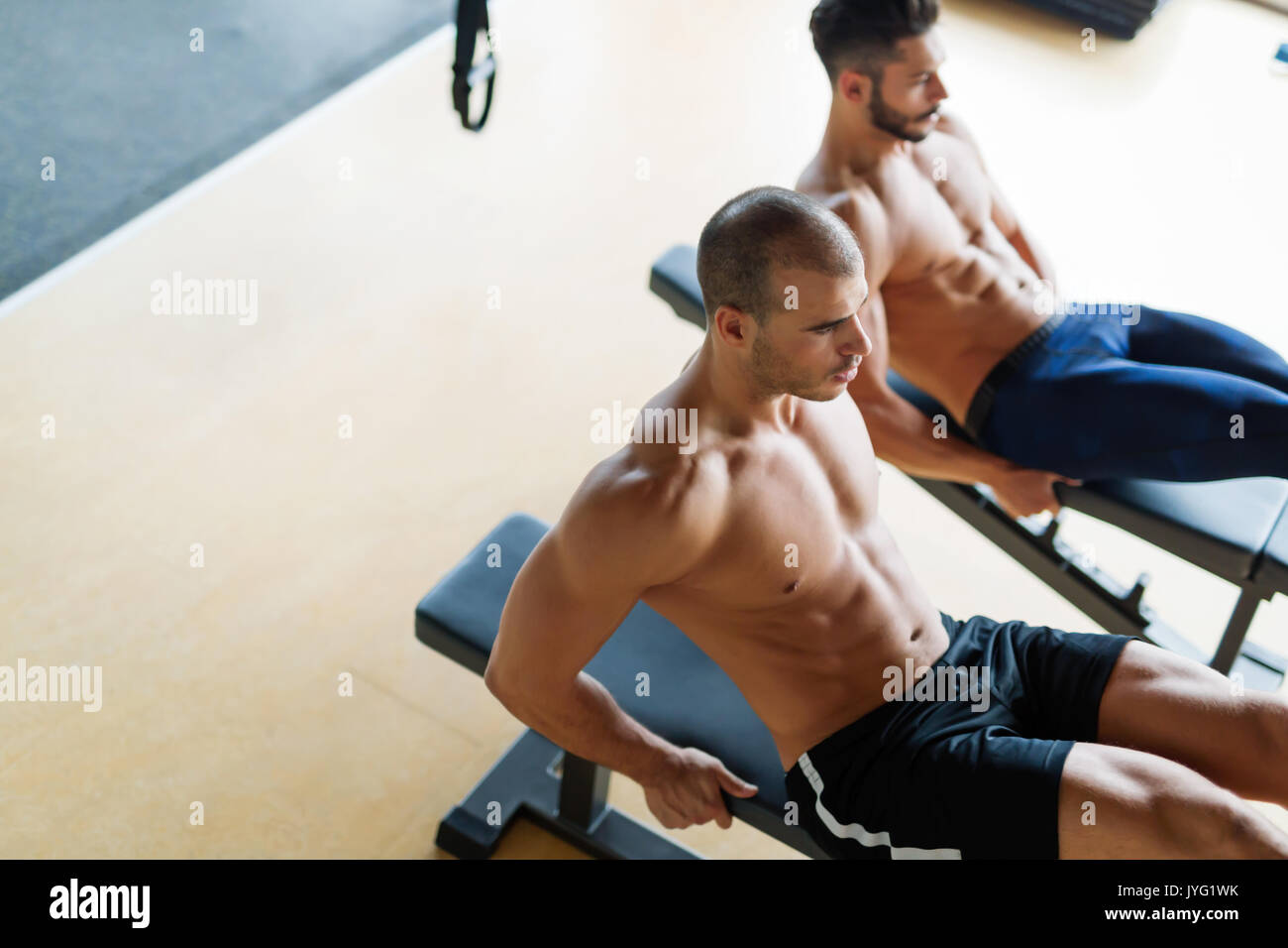 Strong men are doing abs crunches on bench Stock Photo