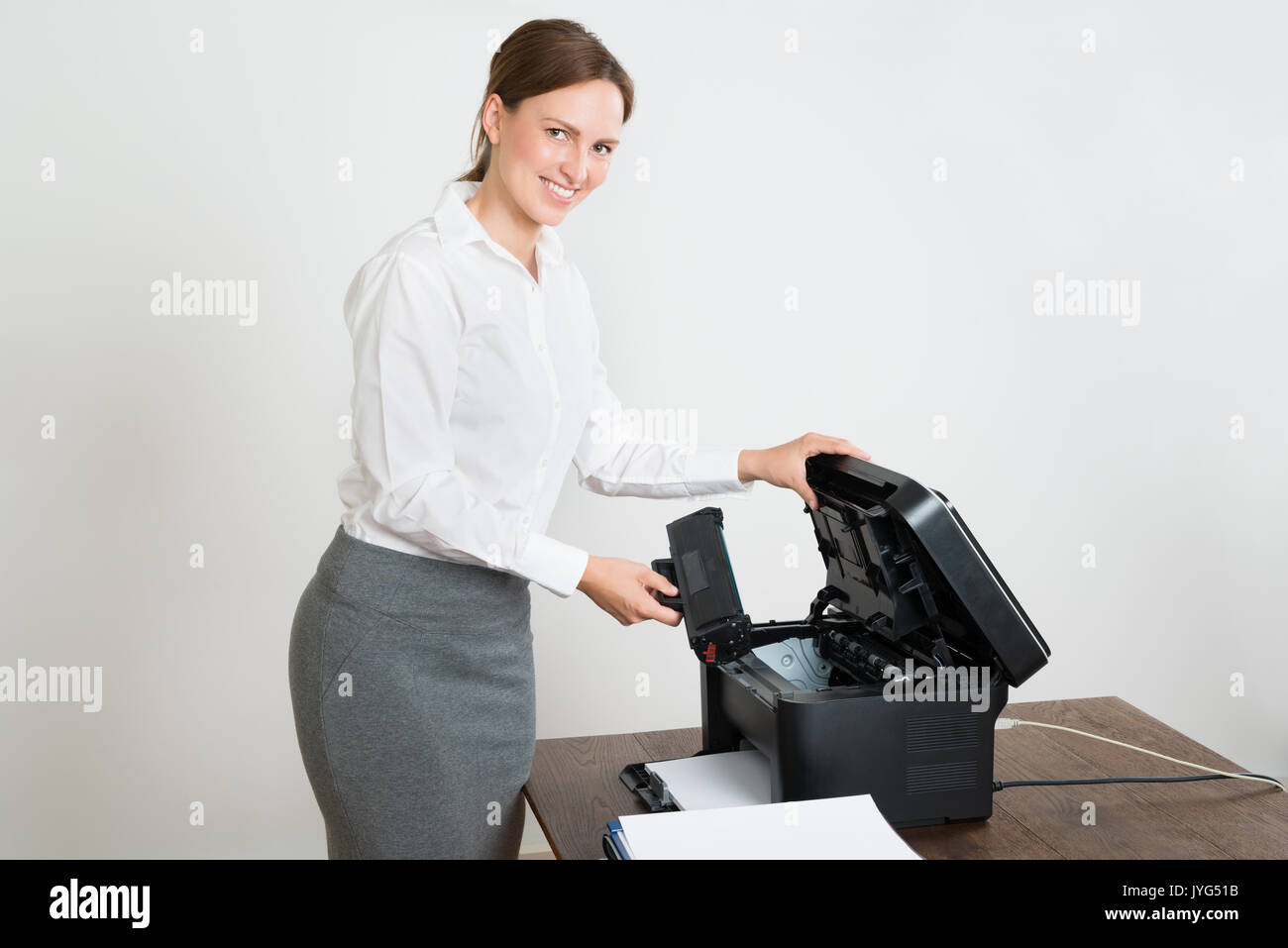 Young Happy Businesswoman Holding Laser Cartridge With Printer At Desk Stock Photo