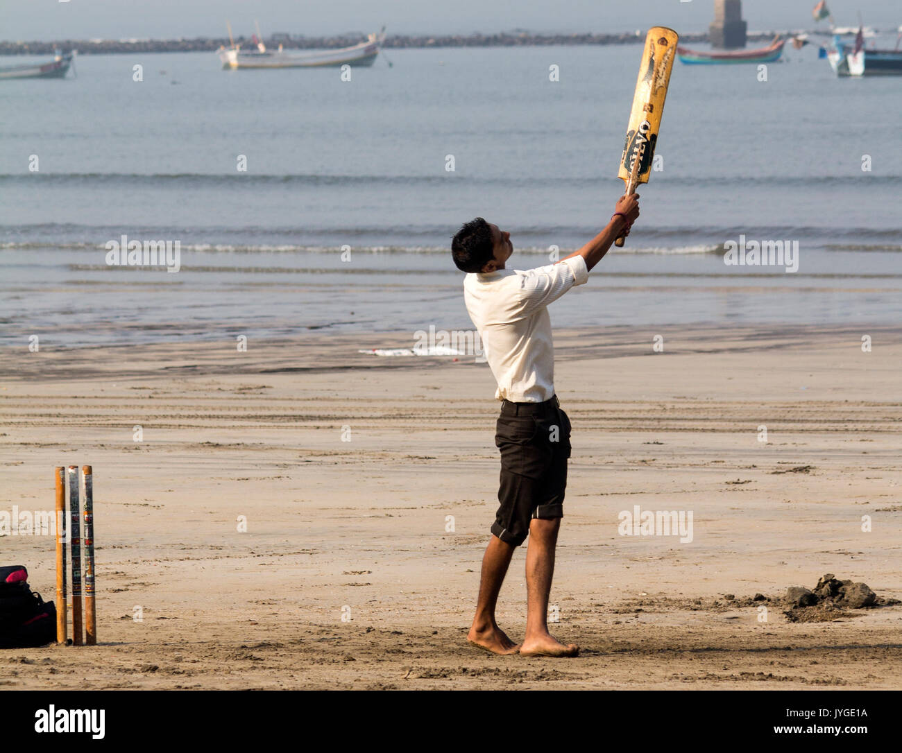 Boy playing cricket at the beach Stock Photo