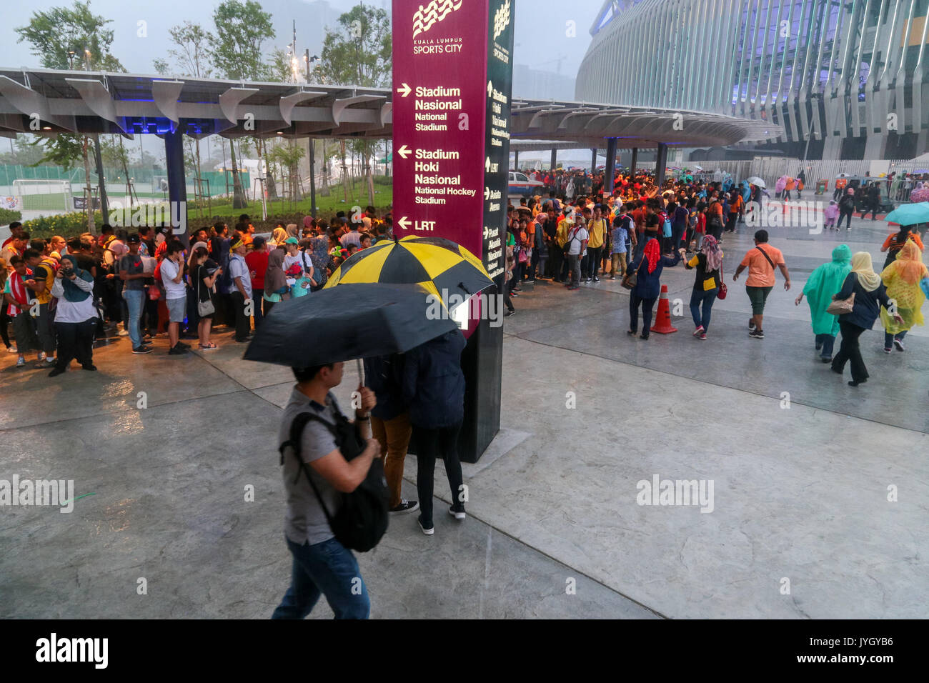 Crowd go under the shade when heavy rain suddenly pour down during the opening ceremony of 29th SEA games. Credit: Calvin Chan/Alamy Live News Stock Photo