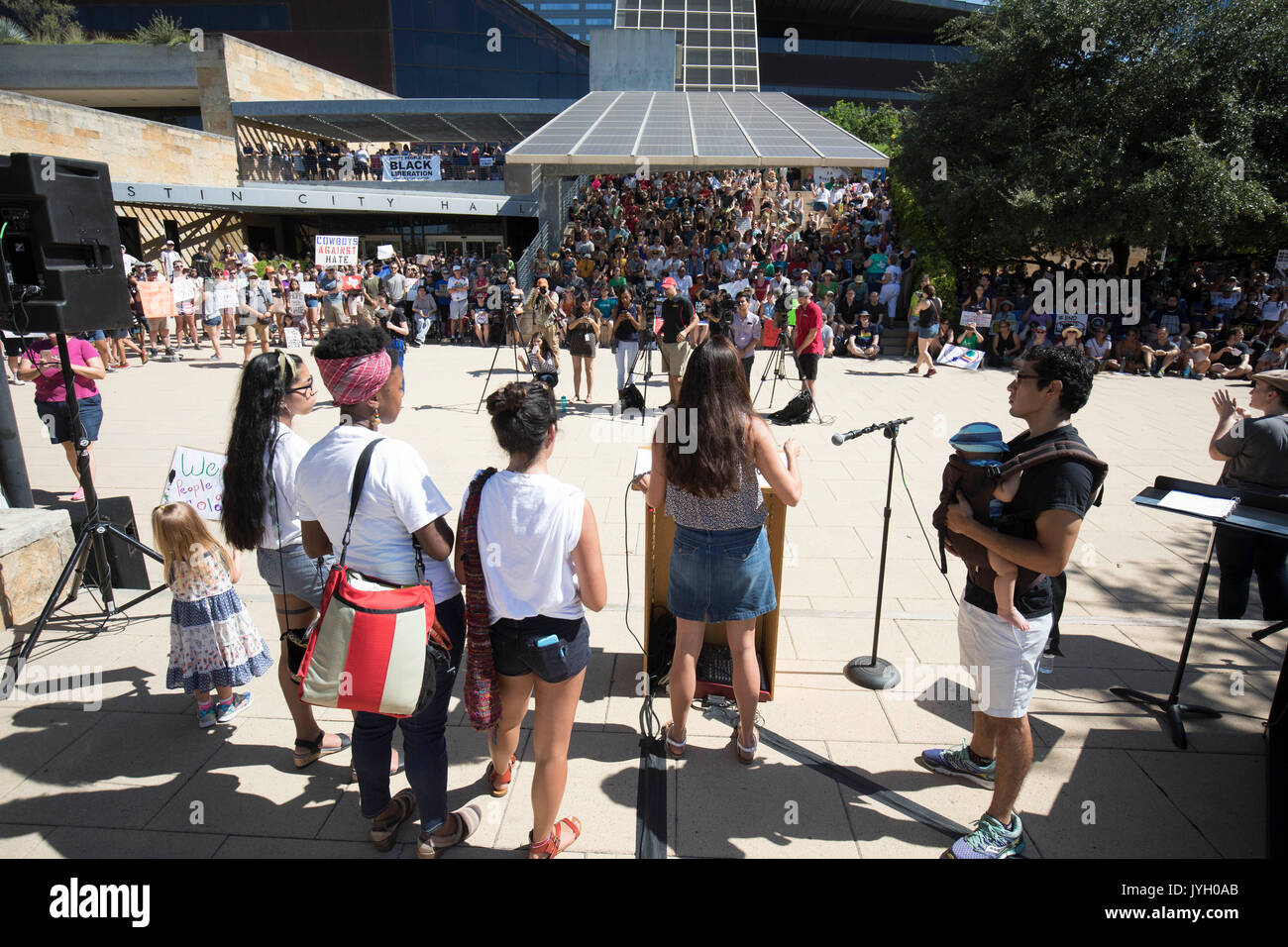 Young woman speaks to activists and protesters at Austin City Hall for a hot two-hour rally against racism and President Donald Trump's apparent insensitive comments about recent Charlottesville violence that left one dead. About 1,000 gathered in the August Texas heat. Stock Photo