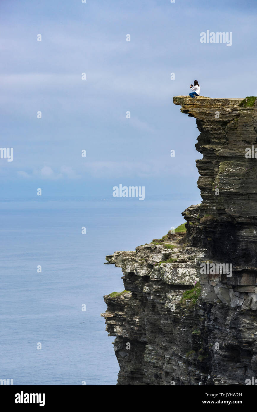Woman on the edge of a cliff at Cliffs of Moher, Liscannor, Munster, Co ...