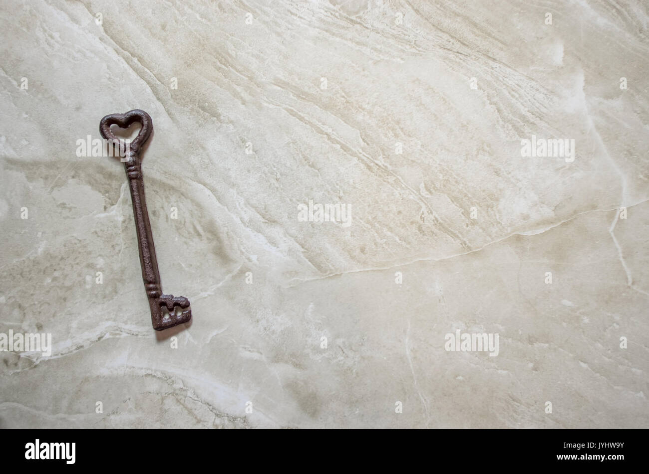 Antique key with heart shape on marble background Stock Photo