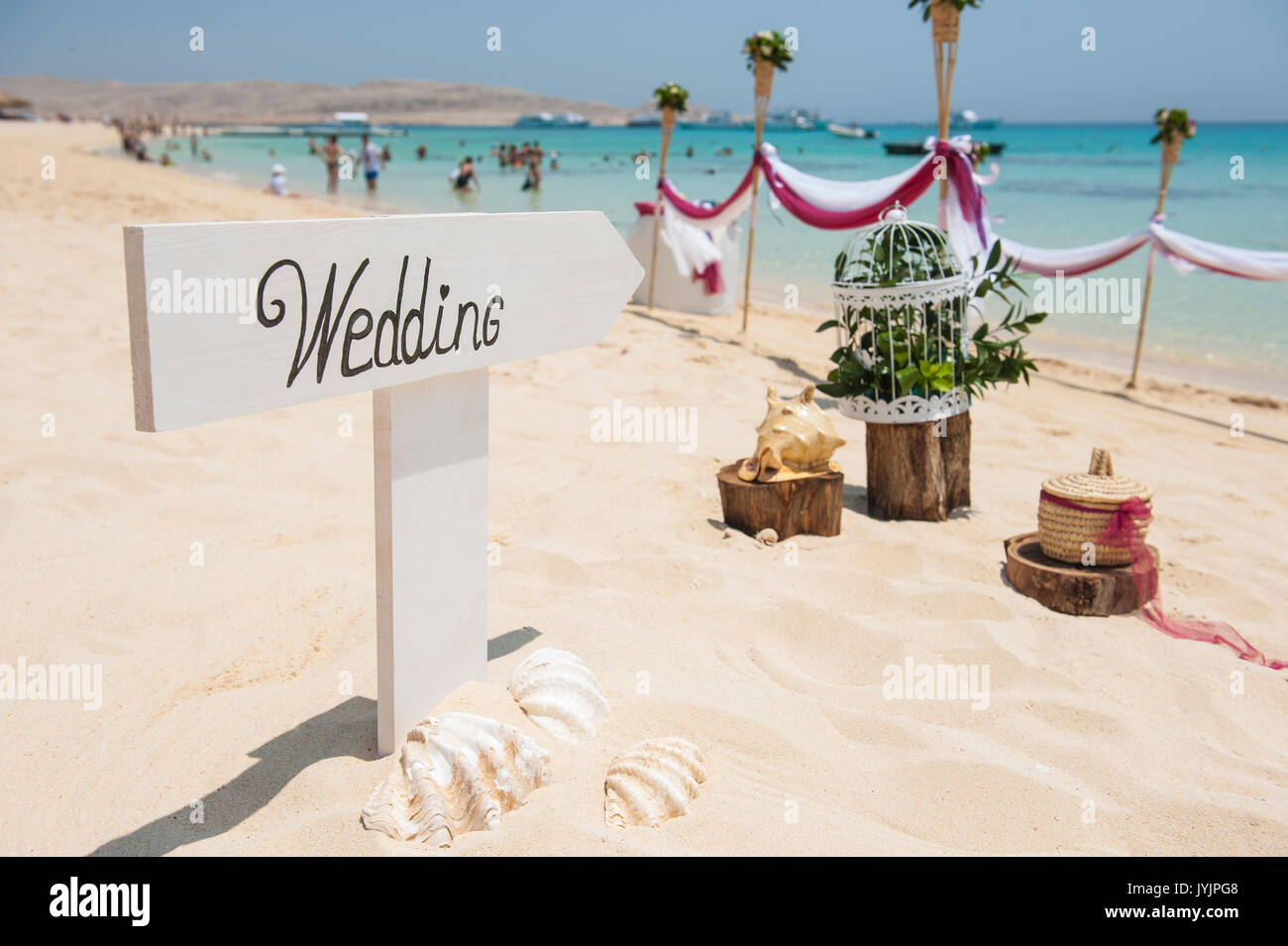 Wooden sign with wedding writing on it and shells in sand of tropical ...