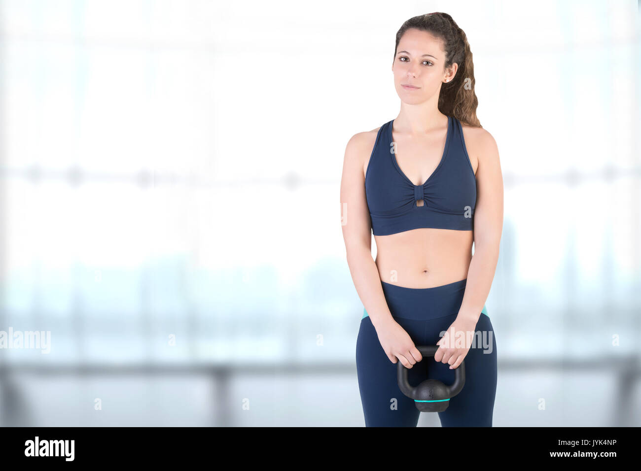 Fit woman working out with a kettlebel and similing in a gym Stock Photo