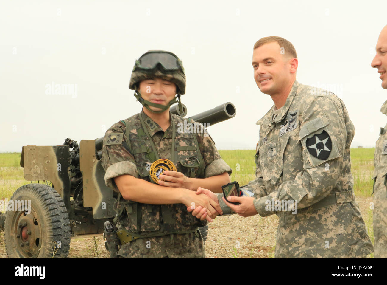 Chief Warrant Officer 2 Brenden Enns, a CH-47 Chinook helicopter pilot from 3rd Battalion, 2nd Aviation Regiment (General Support Aviation Battalion), 2nd Combat Aviation Brigade, 2nd Infantry ROK-US Combined Division, and a soldier from the Myung-Po Field Artillery Battalion, Republic of Korea Army, exchange unit insignia August 17, 2017, in a gesture representing the partnership between these US and ROK units whose joint artillery sling-load movement training demonstrates the solidarity of the two countries in deterrence and defense on the Korean peninsula. Stock Photo