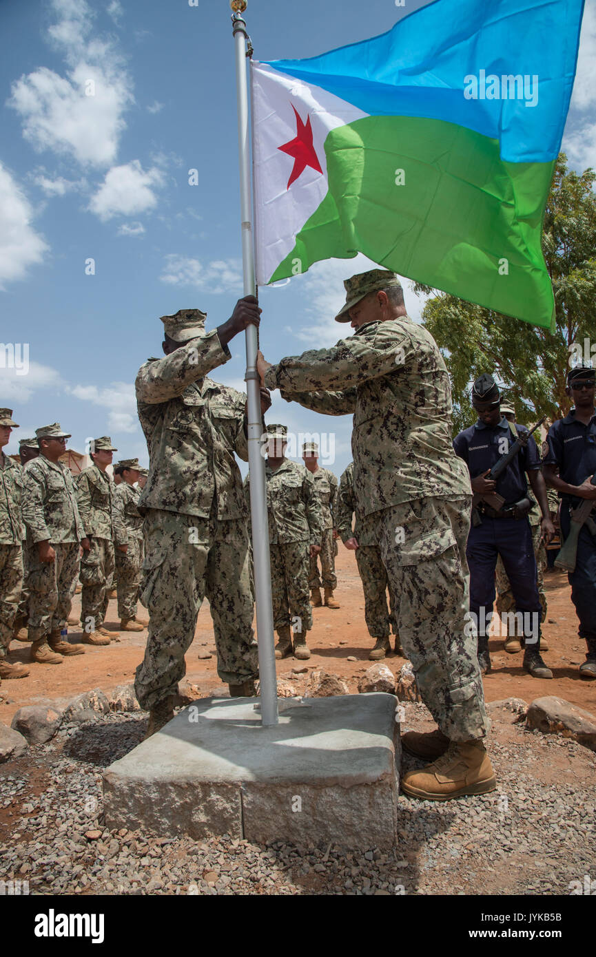 U.S. Navy Chief Petty Officer John Young raises the Djiboutian flag dedicated to the local Village Chief Hassan Diama as Seabees assigned to Combined Joint Task Force-Horn of Africa gather for the flag ceremony in the Arta region, Djibouti, where they are building a medical center, Aug. 17, 2017. The project was started by Naval Mobile Construction Battalion ONE (NMCB 1) and is being relieved by NMCB 133 who will continue working on the project with plans of completion in 2018. (U.S. Air National Guard photo by Tech. Sgt. Joe Harwood) Stock Photo