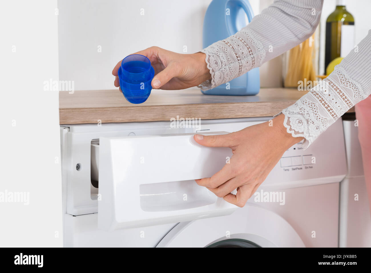 Close-up Of Female Hands Pouring Liquid Detergent In The Washing Machine At Home Stock Photo