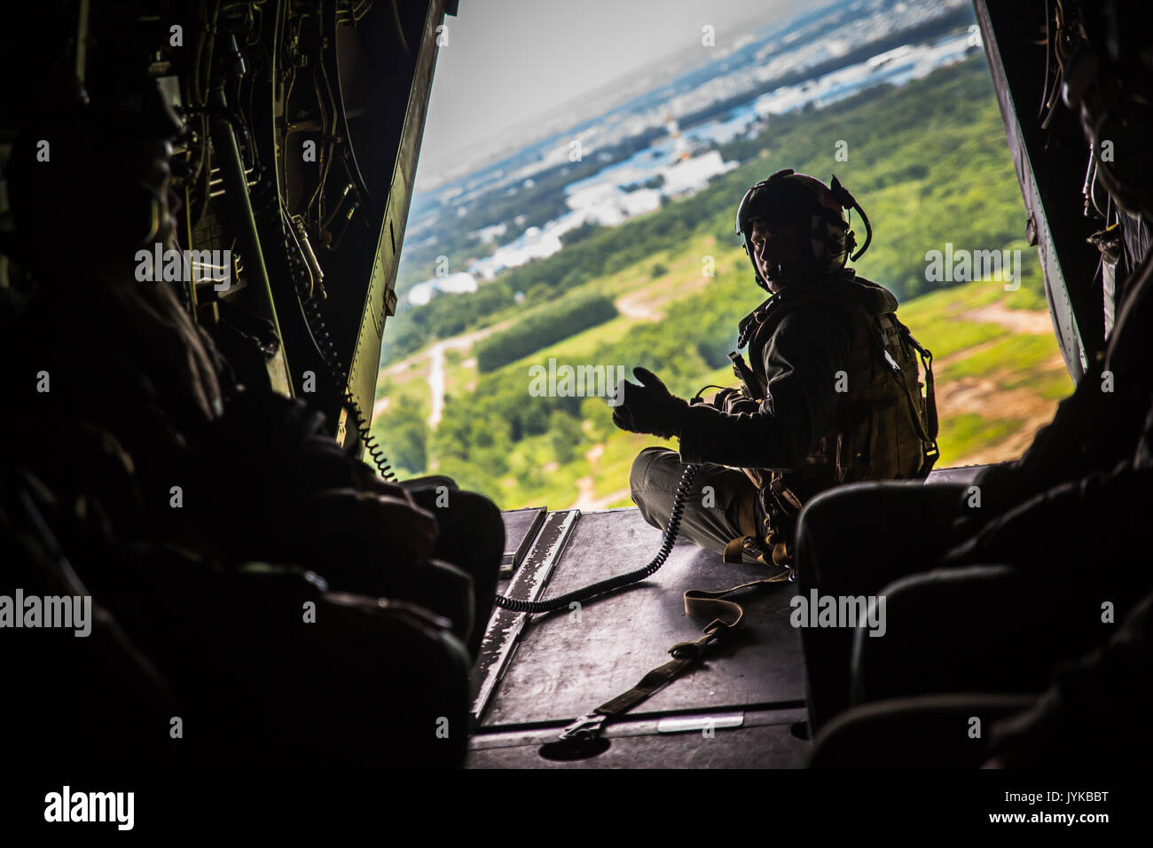 A U.S. Marine Corps crew chief sits on a MV-22 Osprey flying over Hokkaido, Japan, August 18, 2017, in support of Northern Viper 2017. This exercise tests the interoperability and bilateral capability of the Japan Ground Self-Defense Force and U.S. Marine Corps forces to work together and provides the opportunity to conduct realistic training in an unfamiliar environment. This combined-joint exercise is held to enhance regional cooperation between participating nations to collectively deter security threats. The crew chief is assigned to Marine Medium Tiltrotor Squadron 262, Marine Aircraft Gr Stock Photo