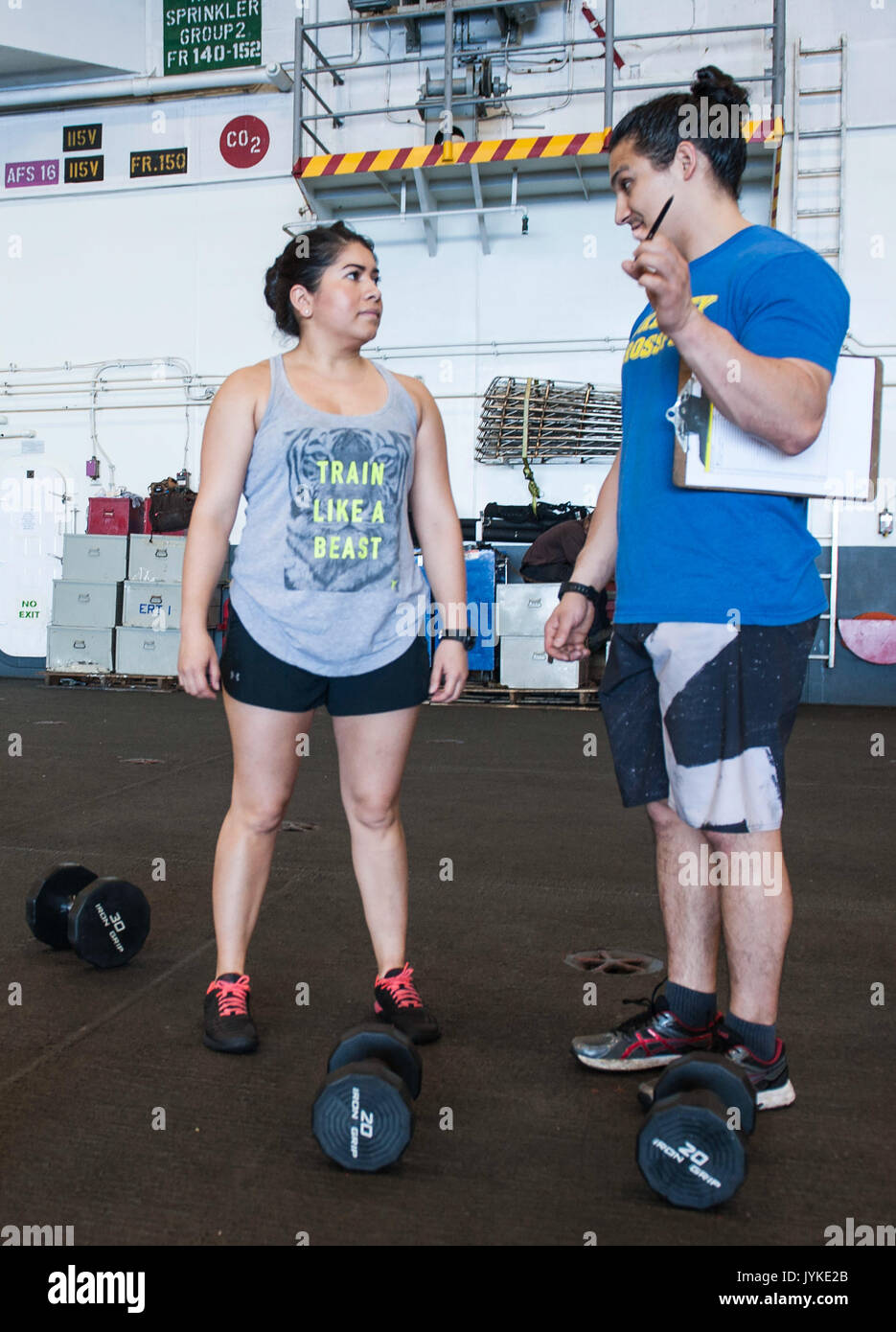 170815-N-RZ514-091 ATLANTIC OCEAN (Aug. 15, 2017) Air Traffic Controller 3rd Class Tania Ramirez, left, receives instruction from 'Fit Boss' Justin Vigil before participating in a 'Battle for the Dumbbell' competition the hangar bay aboard the aircraft carrier USS George H.W. Bush (CVN 77).  The ship and its carrier strike group are conducting naval operations in the U.S. 6th Fleet area of operations in support of U.S. national security interests.  (U.S. Navy photo by Mass Communication Specialist Seaman Jennifer M. Kirkman/Released) Stock Photo