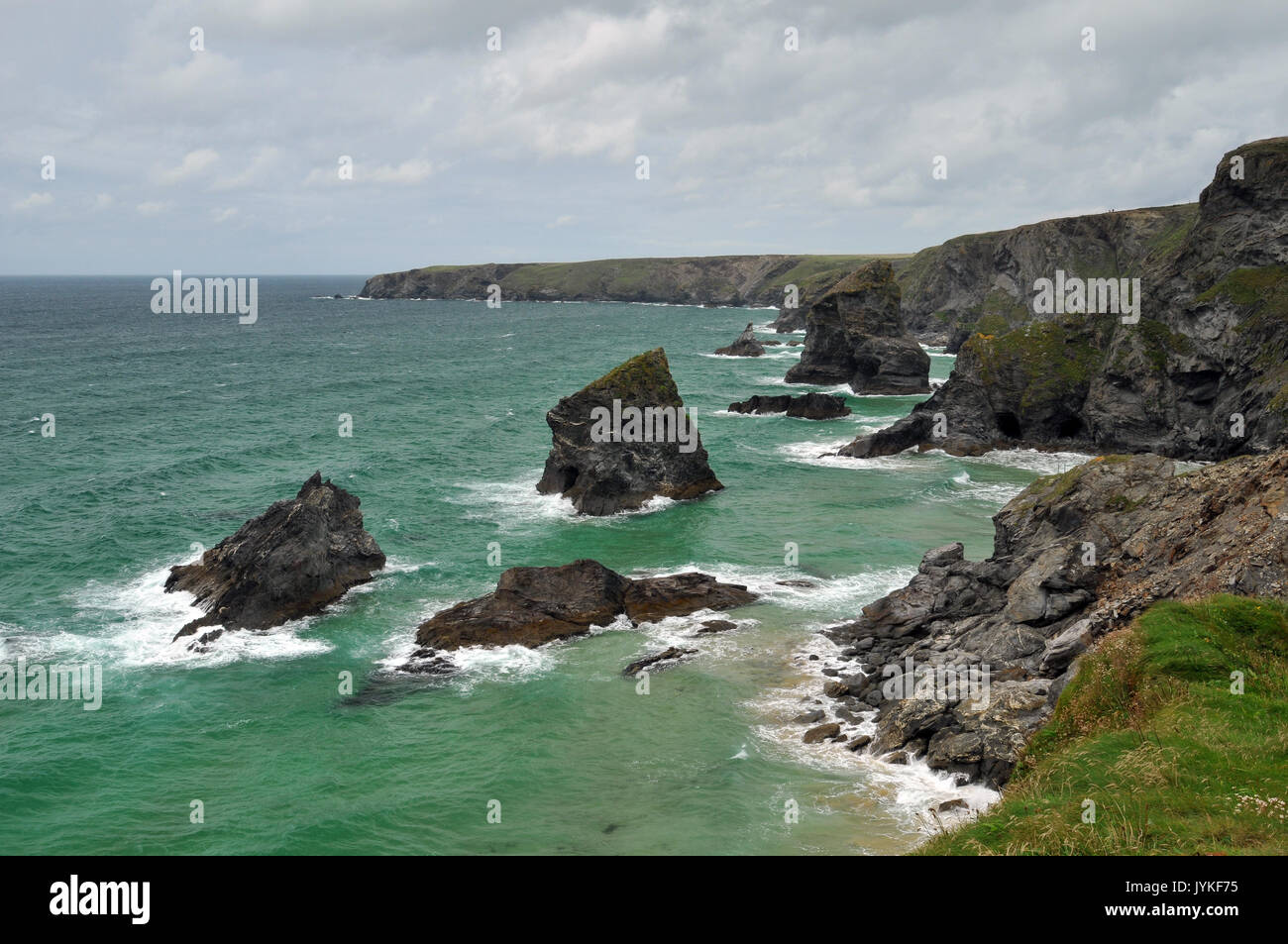 the rocks and sea at bedruthan steps national trust land or site in north cornwall showing moody slies sky and rugged coastline with surf and rocky Stock Photo